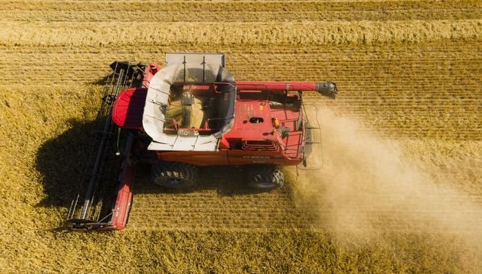 red combine harvester in field from above